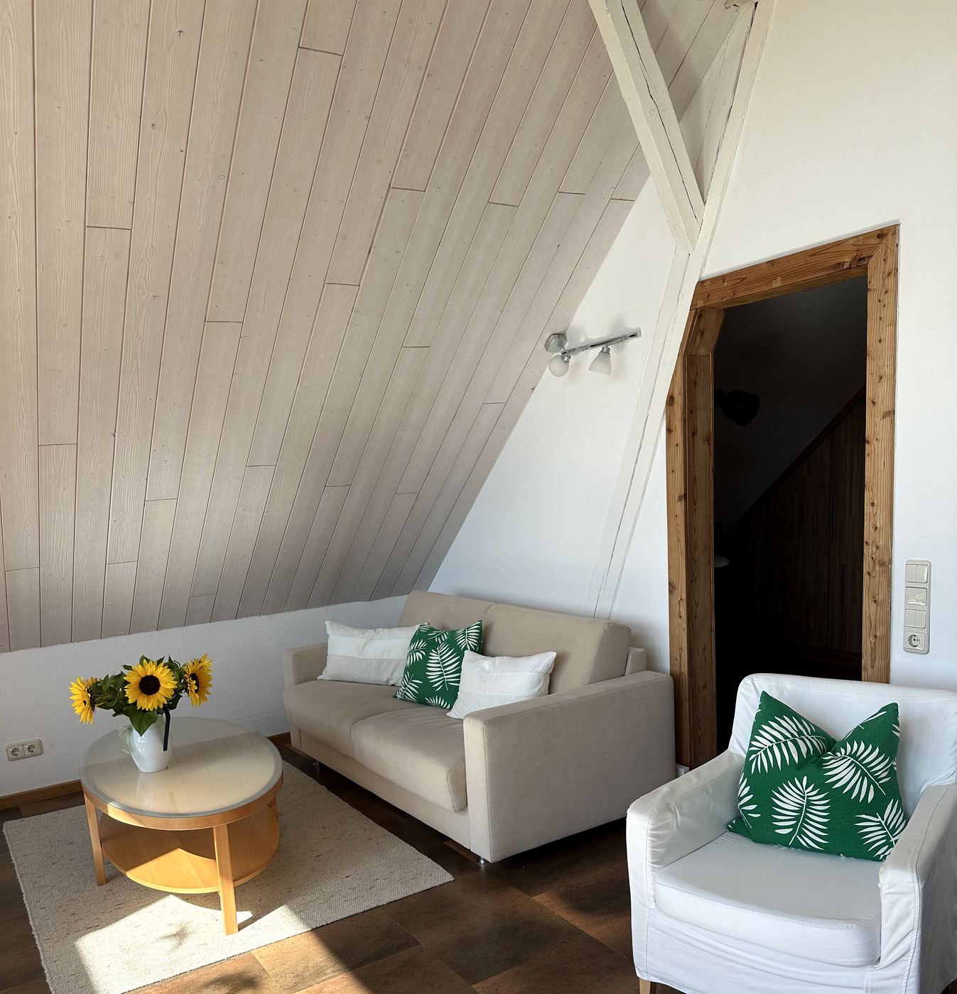 Sitzgruppe aus Sofa und Sessel unter der Dachschräge, daneben der Durchgang zur Treppe