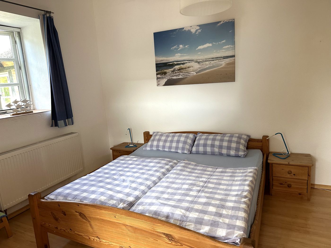 Schlafzimmer mit Doppelbett und Ostseebild über dem Kopfteil