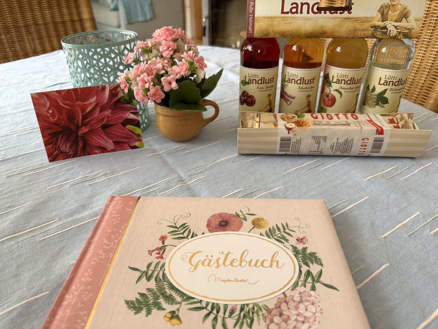 Gästebuch, Blumen und Saftflaschen als Willkommensgruß auf dem Tisch